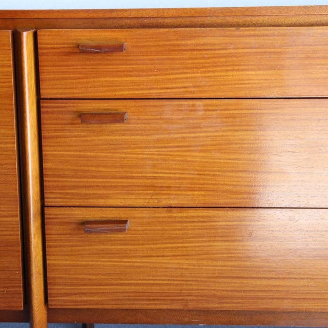 Vintage British mid-century teak sideboard with smooth wood grain and recessed handles on drawers.