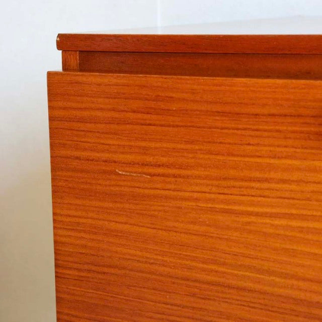 Mid-century British vintage sideboard in teak with warm wood grain and clean lines, minimalistic top edge detail.