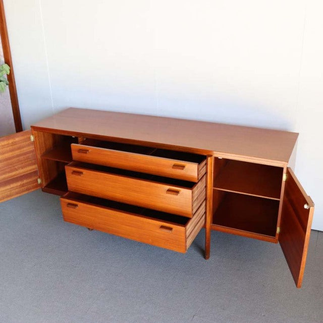 Mid-century British vintage teak sideboard with rich wood grain, three central drawers, and two open door cabinets on each.