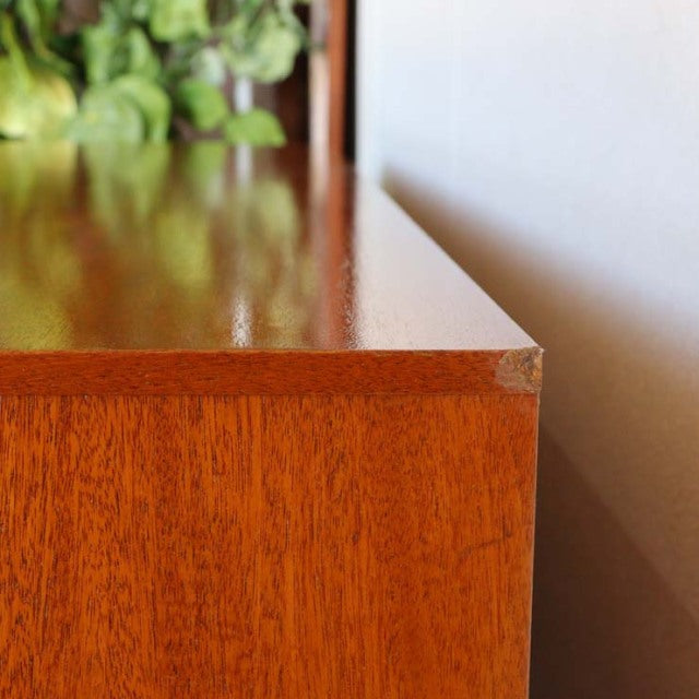 Close-up of vintage British mid-century teak sideboard corner showing rich wood grain and smooth polished finish.