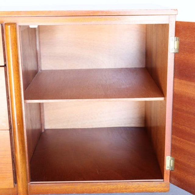 Mid-century British vintage teak sideboard open door showing rich wood grain, brass hinges, and interior shelf.