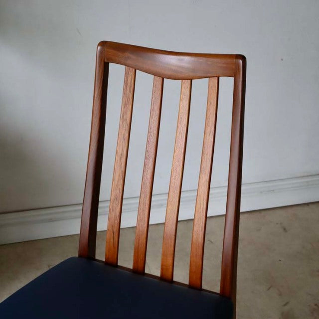 Vintage British mid-century teak dining chair with vertical slat back and dark upholstered seat.