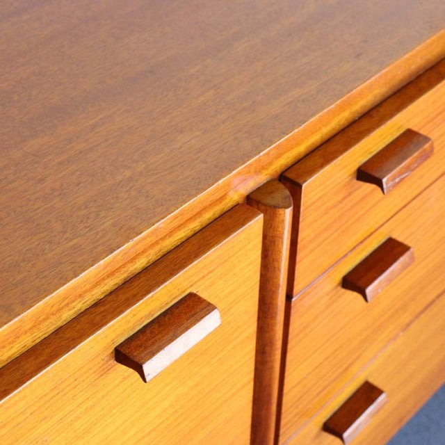 Vintage teak British mid-century sideboard with rich wood grain and rectangular wooden handles.
