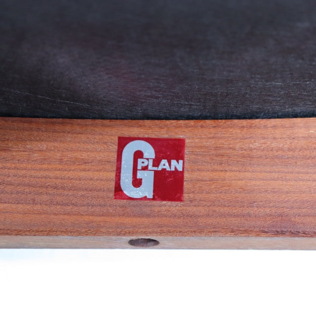 Close-up of vintage British G-Plan teak dining chair label on mid-century wooden frame with visible grain.