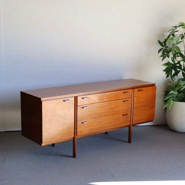 Mid-century British vintage teak sideboard with smooth wood grain, clean lines, and slender legs, sleek rectangular form.