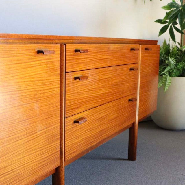 Mid-century British vintage teak sideboard with rich wood grain, tapered legs, and minimalist rectangular handles.