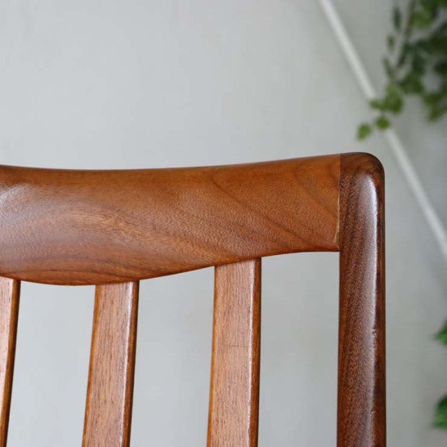 Close-up of mid-century British G-PLAN vintage teak dining chair backrest with smooth wood grain and rounded edges.