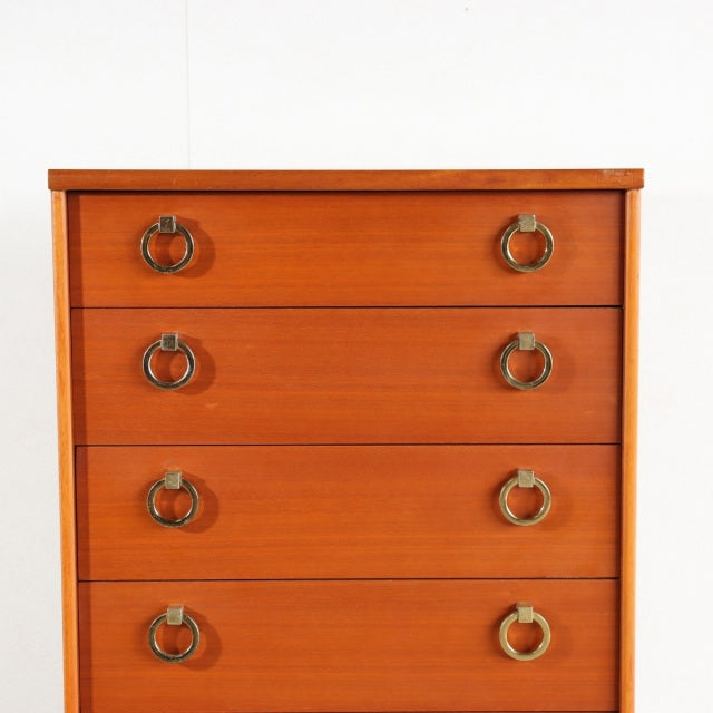 Vintage British mid-century teak chest with four drawers, brass ring handles, and clean lines.