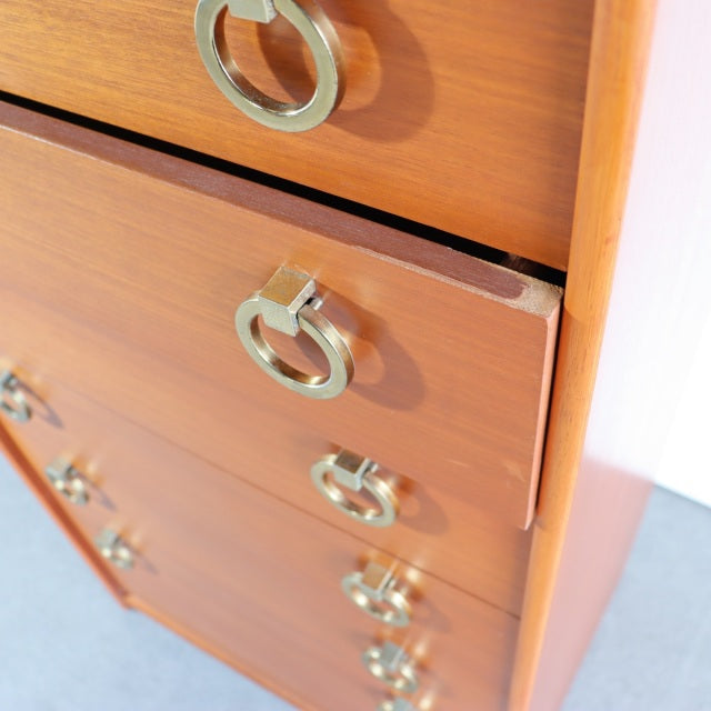 Vintage British mid-century teak chest with golden circular metal handles and visible wood grain, sleek legs, smooth edges.