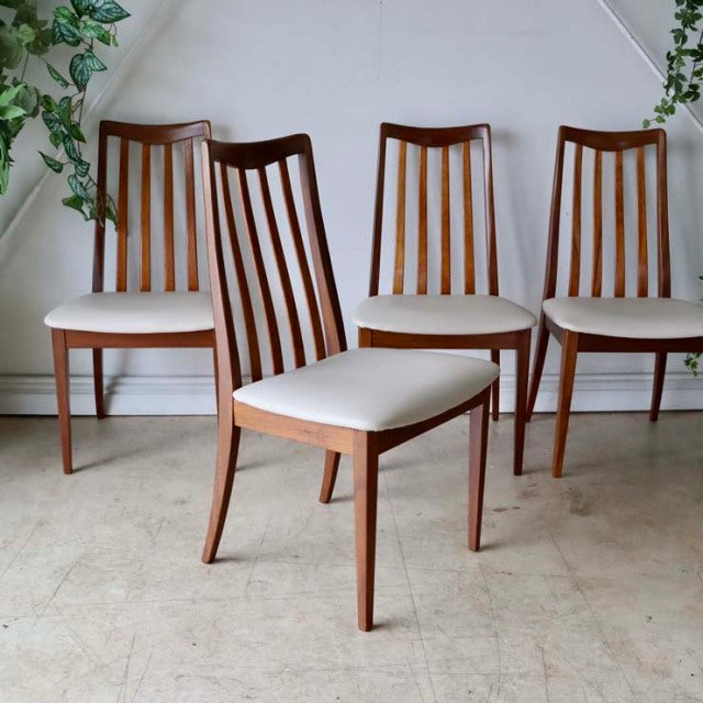 Set of four vintage G-PLAN teak dining chairs with mid-century British design, ivory upholstered seats, and elegant tapered.