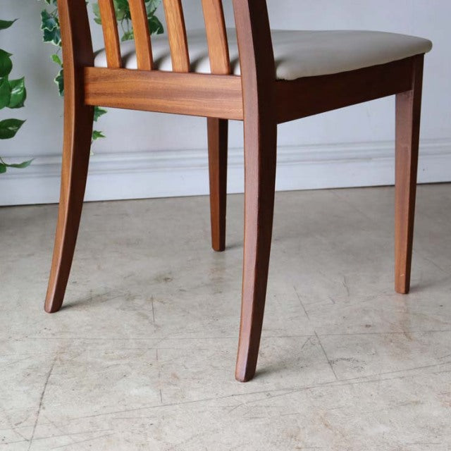 Mid-century British G-Plan dining chair in teak with a slatted backrest and ivory reupholstered seat, smooth wood grain.