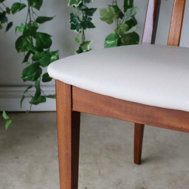 Vintage British mid-century teak dining chair with ivory upholstered seat and tapered legs.