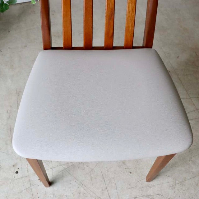 Mid-century British G-Plan dining chair with teak wood frame and ivory upholstered seat, visible wood grain on slatted back.