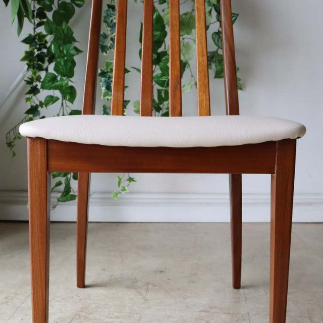 Vintage British mid-century teak dining chair with vertical slat back and ivory upholstered seat.