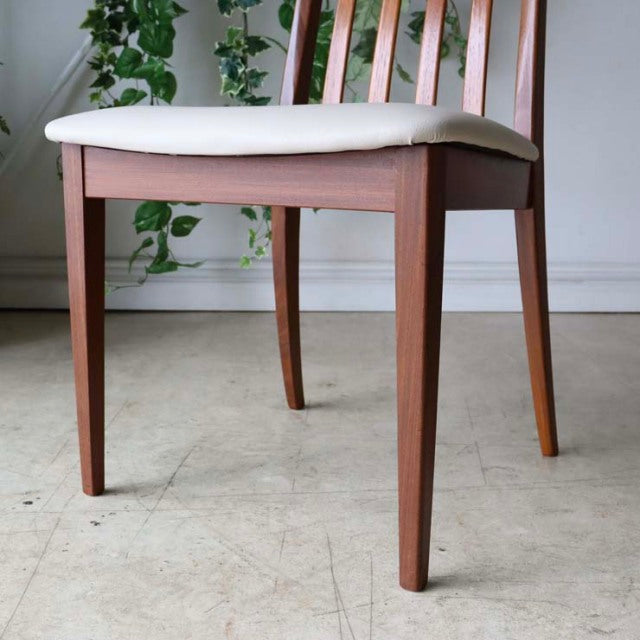 Mid-century British vintage teak dining chair with ivory upholstered seat and tapered legs.