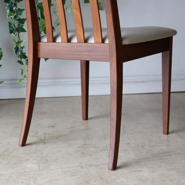 Mid-century British G-Plan dining chair set of four in teak with ivory upholstered seats and slatted backs.