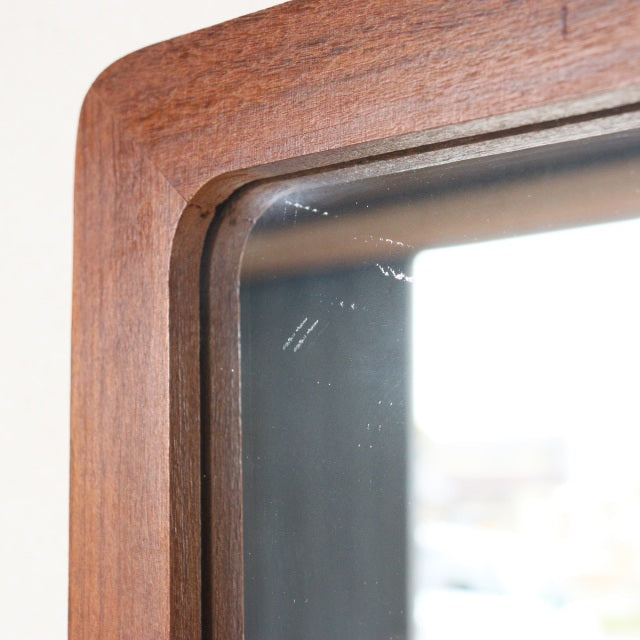 Mid-century British vintage wall mirror with trapezoid teak frame showcasing rich wood grain and smooth rounded edges.