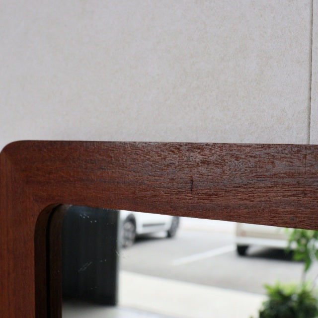 Mid-century British vintage teak wall mirror with trapezoid shape and smooth wood grain finish.