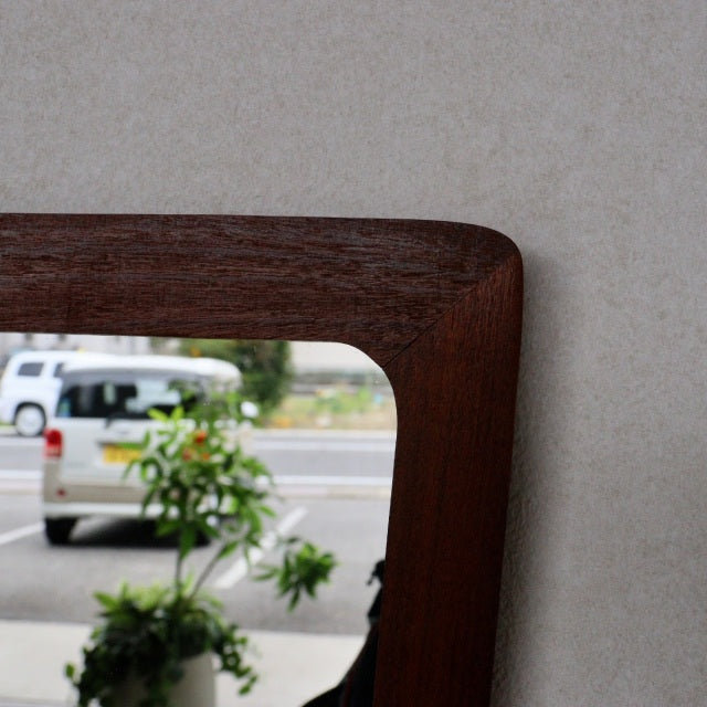 Mid-century British vintage wall mirror with trapezoid teak frame featuring rich wood grain and smooth rounded edges.