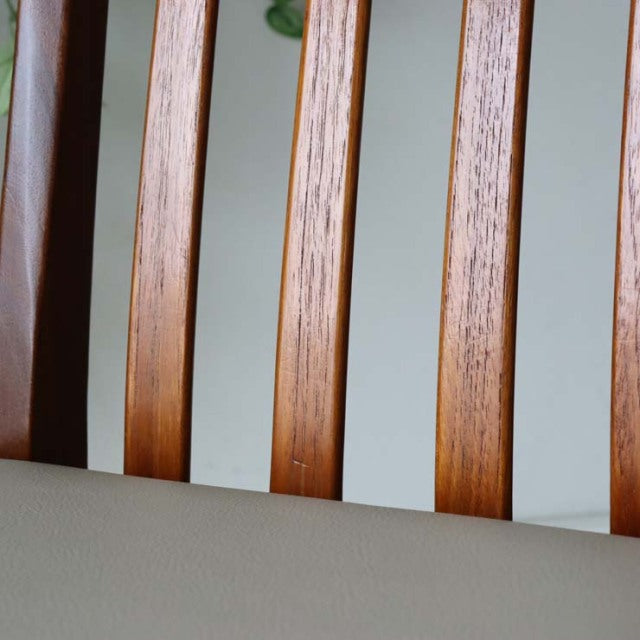 Close-up of vintage British mid-century teak dining chair backrest with vertical slats and ivory upholstered seat.