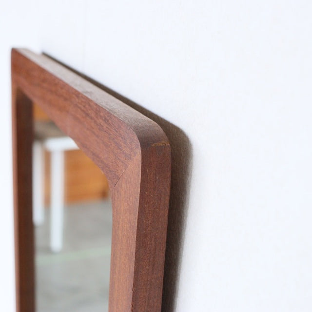 Vintage British mid-century teak trapezoid wall mirror with smooth wood grain and rounded edges.