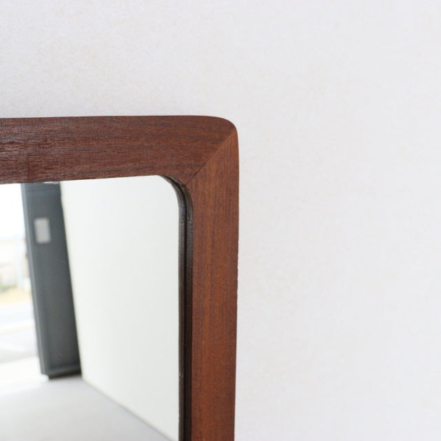 Vintage mid-century British teak trapezoid wall mirror with smooth rounded edges and fine wood grain detail.