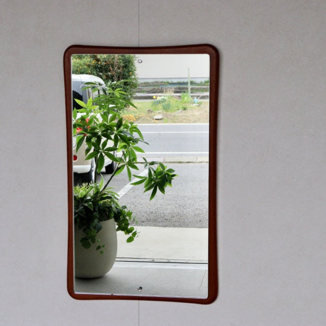 Mid-century British teak wall mirror with gently curved rectangular frame and smooth wood grain finish.