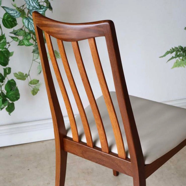 Mid-century British vintage teak dining chair with curved slatted back and ivory upholstered seat.