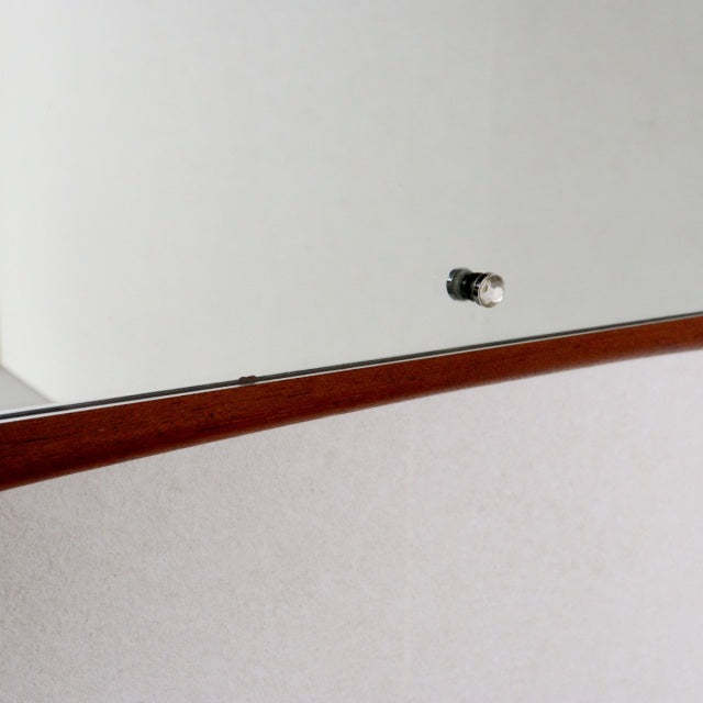 Mid-century British teak wall mirror with gently curved frame and visible wood grain detail.