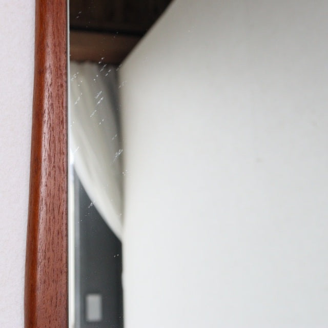 Mid-century British vintage teak wall mirror with gently curved frame and rich wood grain.