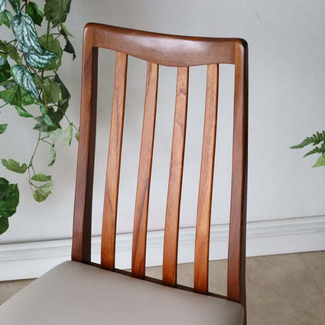 Vintage mid-century British teak dining chair with vertical slatted backrest and ivory upholstered seat.
