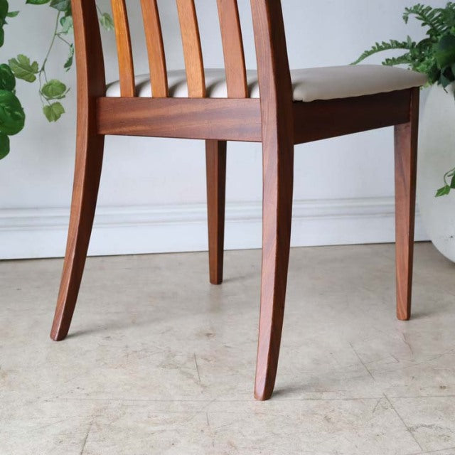 Mid-century British G-PLAN teak dining chair with curved slatted back and ivory upholstered seat.