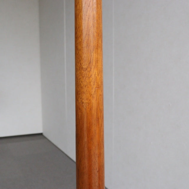 Mid-century vintage British teak floor lamp with smooth wood grain and slender cylindrical column.