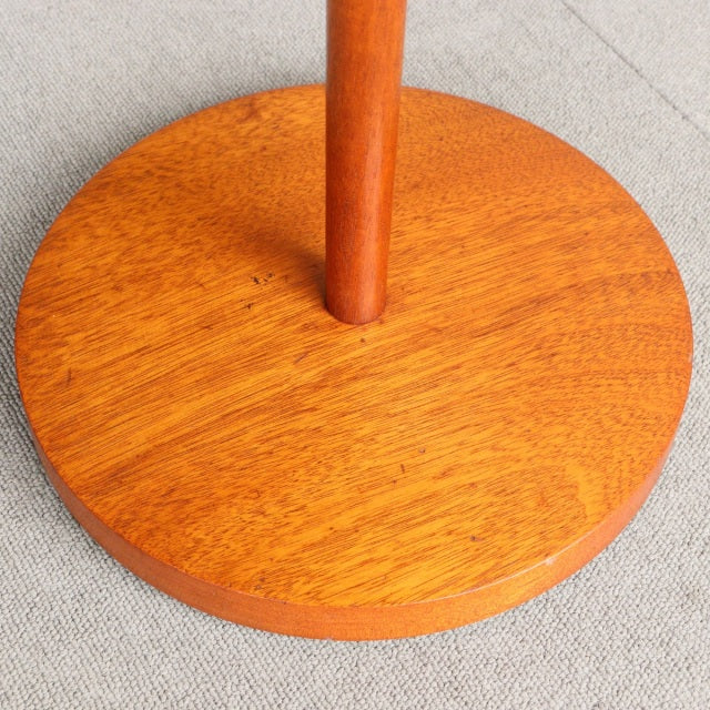 Round teak base of vintage British mid-century floor lamp with warm wood grain and smooth finish.