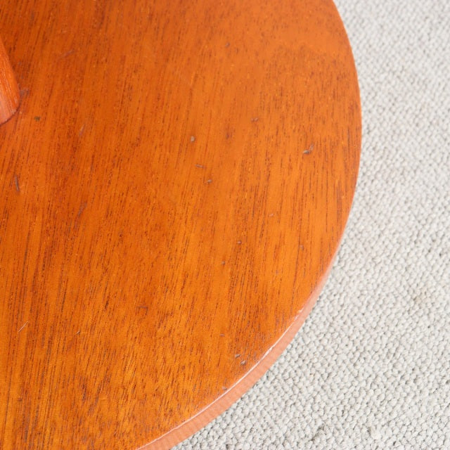 Round vintage teak tabletop with rich wood grain and warm mid-century British finish on textured beige carpet.