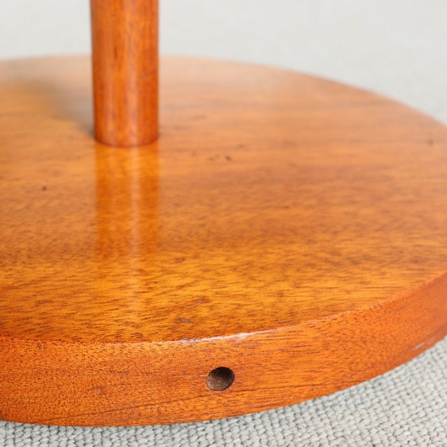Close-up of round vintage teak base with warm wood grain and smooth finish on mid-century British floor lamp.