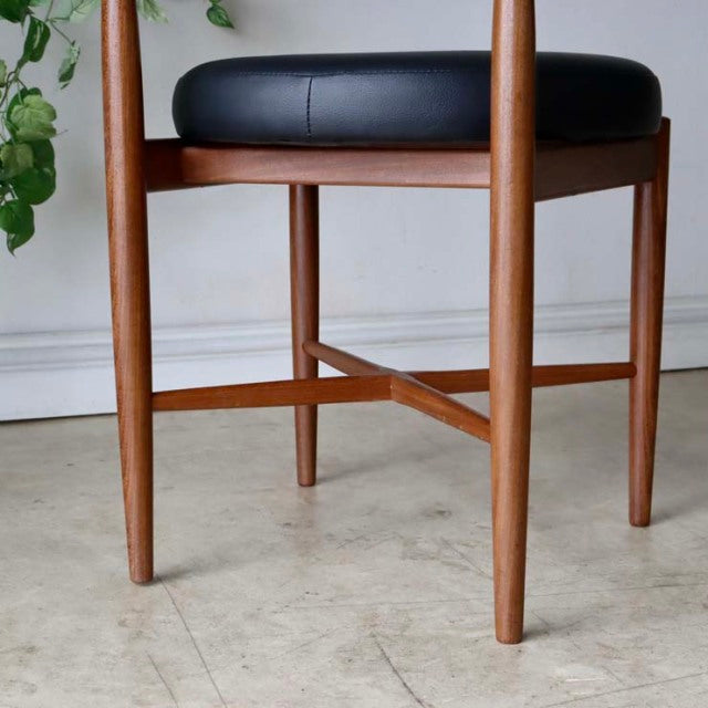 Set of four vintage British mid-century G-Plan dining chairs in teak with slender tapered legs and black leather seats.