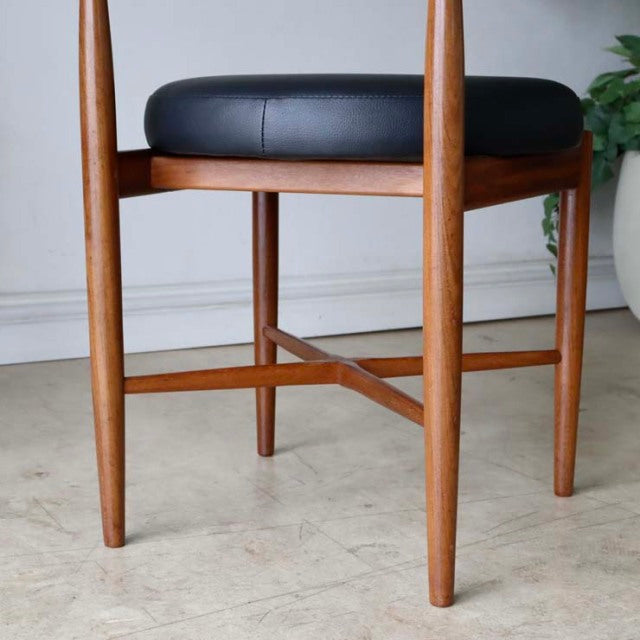 Set of four vintage G-Plan teak dining chairs with mid-century British design, black cushioned seats, and tapered legs with.