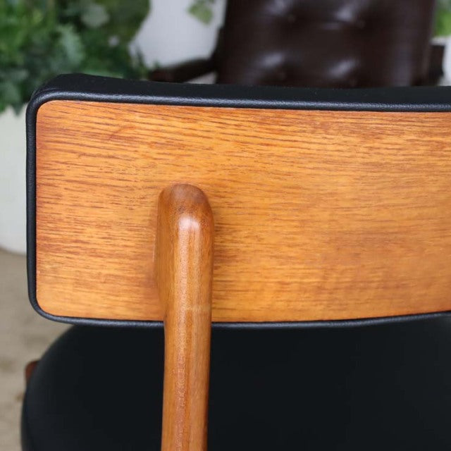 Vintage British G-Plan mid-century teak dining chair backrest with smooth wood grain and black cushioned seat edge.