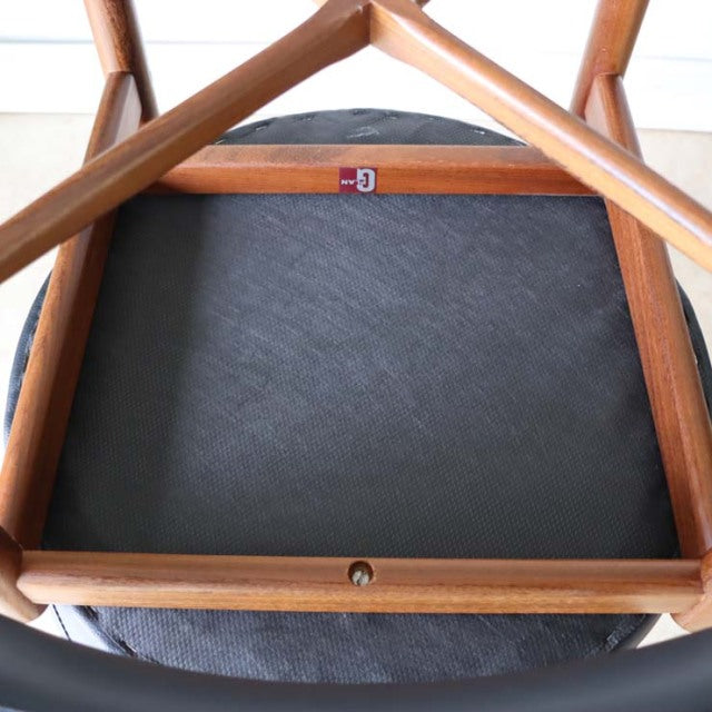 Vintage G-plan mid-century teak dining chair underside showing wood grain frame and black upholstered seat.