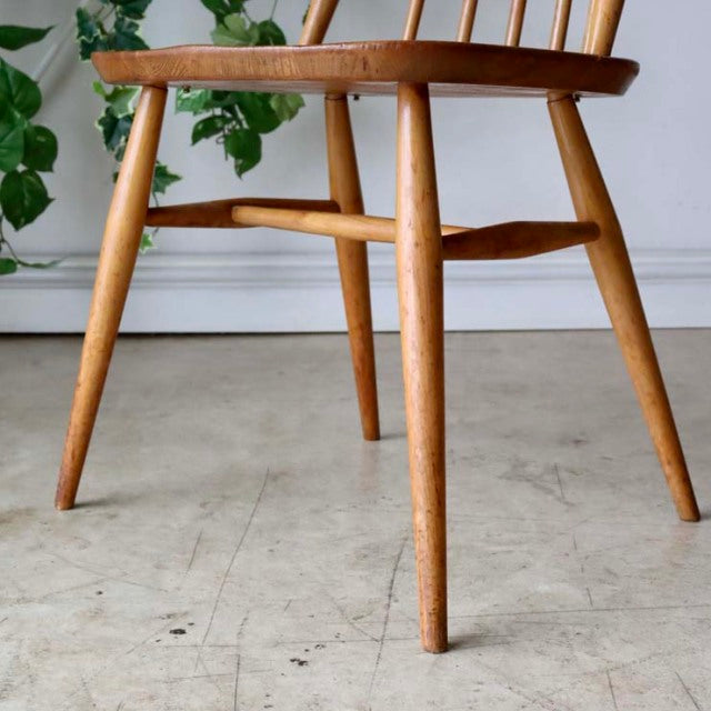 Mid-century British Ercol Goldsmith chair in natural teak with tapered legs and visible wood grain.