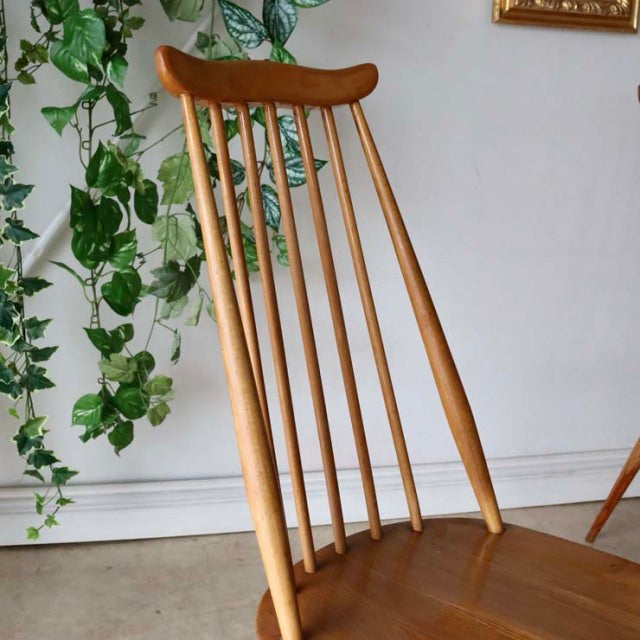 Vintage British Ercol Goldsmith high-back chair in natural teak with slender spindles and smooth wood grain, mid-century.