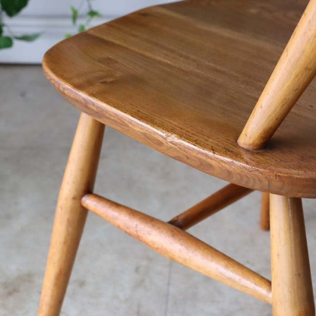 Close-up of vintage British Ercol Goldsmith mid-century teak chair seat and tapered legs with natural wood grain finish.