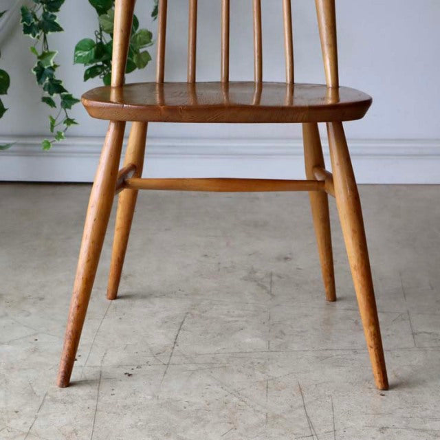 Vintage mid-century Ercol Goldsmith high-back chair in natural teak with slender spindle backrest and tapered legs.