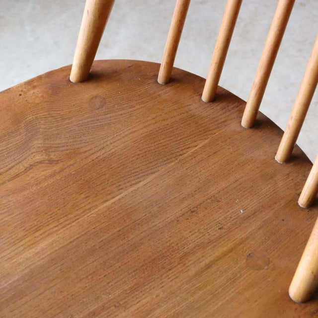 Vintage British mid-century Ercol high-back dining chair in natural teak with smooth wood grain and slender rounded spindles.