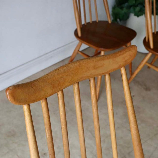 Vintage British Ercol Goldsmith mid-century teak dining chair in natural finish with slender spindle back and rounded edges.