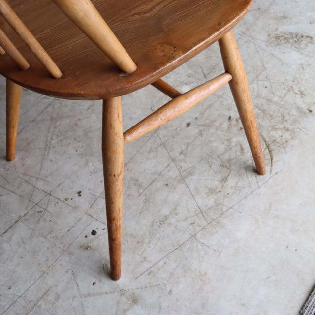 Mid-century British Ercol Goldsmith high-back chair in natural teak with visible wood grain and tapered legs.
