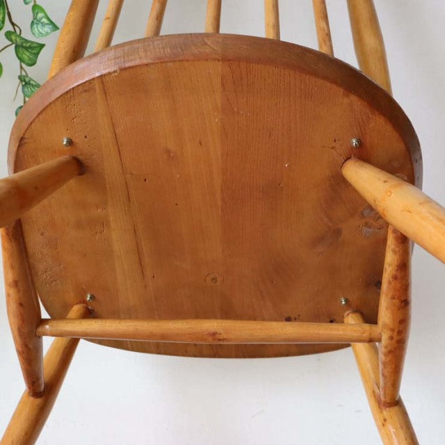 Vintage British mid-century Ercol teak high-back chair viewed from underside, showing smooth wood grain and turned legs in.