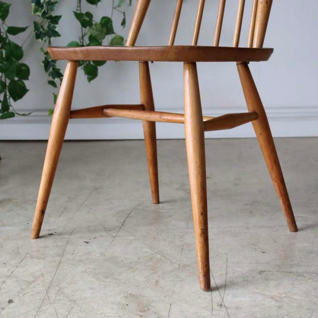 Mid-century British vintage Ercol dining chair in teak with spindle back and tapered legs, smooth wood grain finish.