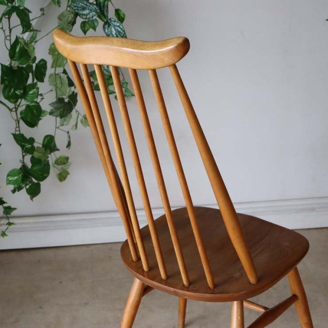 Vintage British Ercol Goldsmith dining chair in mid-century teak with slender spindle back and tapered legs.